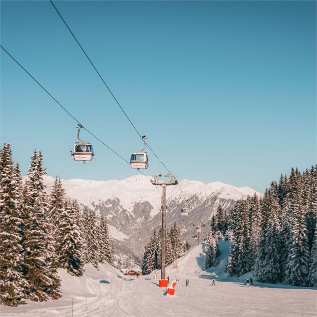 La télécabine de Vizelle passe au dessus d'une piste où des skieurs descendent - Courchevel Tourisme