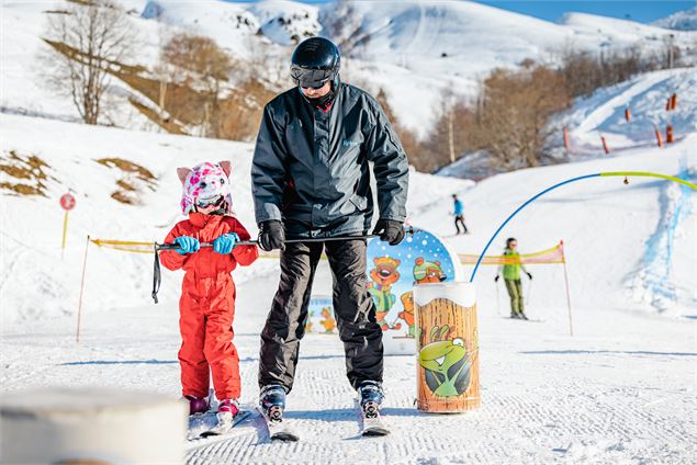 Un parent qui accompagne son enfant dans l'apprentissage du ski - Alpcat Médias