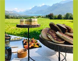 table de brunch dans l'herbe avec vue sur le lac d'Annecy et les montagnes - Oxalys Gastronomie Vaga