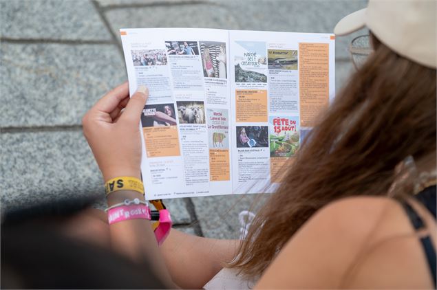 visiteuse du Grand-Bornand lisant le programme des animations d'été au pot d'accueil - L. GOUTTENOIR