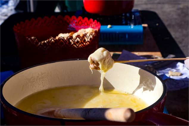 Pain plongé dans la fondue lors de l'atelier fondue à Saint Jean d'Arves - Office de Tourisme de Sai