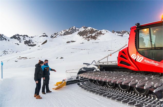 Un dameur et sa cliente qui échangent au pied de la dameuse dans le cadre de Monte dans ma dameuse à