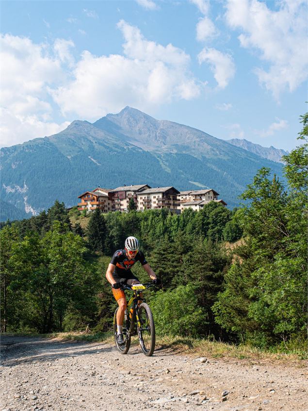 Vttiste sur piste carrosable avec les résidences d'Aussois en arrière Plan et la Pointe de la Norma 