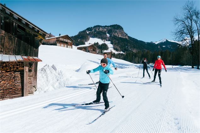 Famille de skieurs sur une piste de ski nordique au Grand-Bornand, près de chalets - C. Hudry