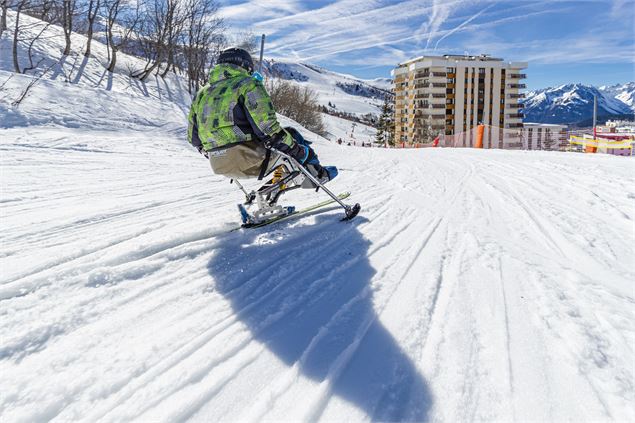 Un homme en fauteuil handiski sur une piste blueue - Alpcat Médias