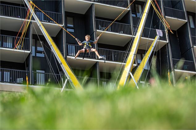 Un garçon faisant de l'Élasto-Bungee avec la vue sur un immeuble en toile de fond - Daniel Durand