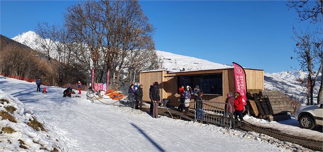 Enfants avec des luges et dégustation de boissons chaudes à la buvette de l'Espace nordique et de lo